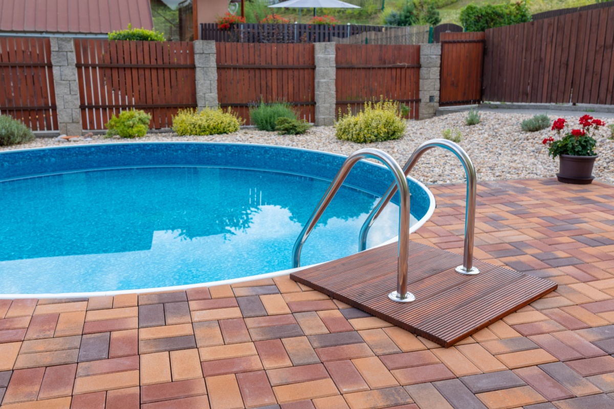 a dark wood fence with brick columns set up around a small, circular pool