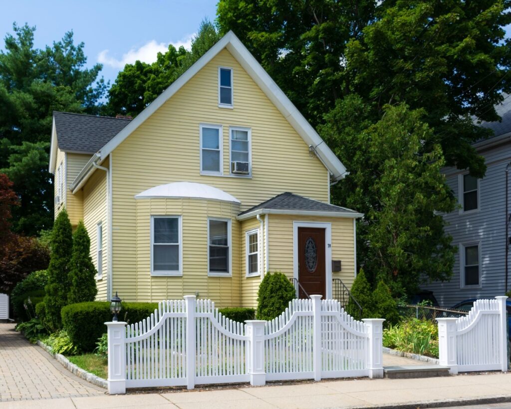 A custom vinyl fence installed in front of a yellow house